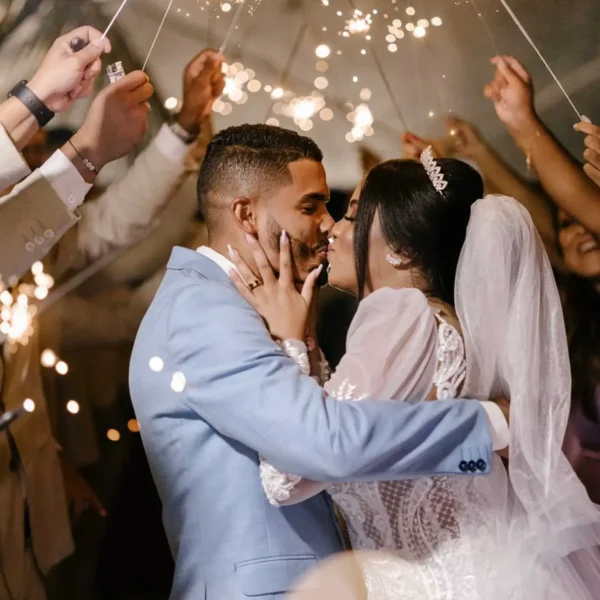 Noivos se beijando entre os padrinhos e madrinhas segurando velas estrelinha